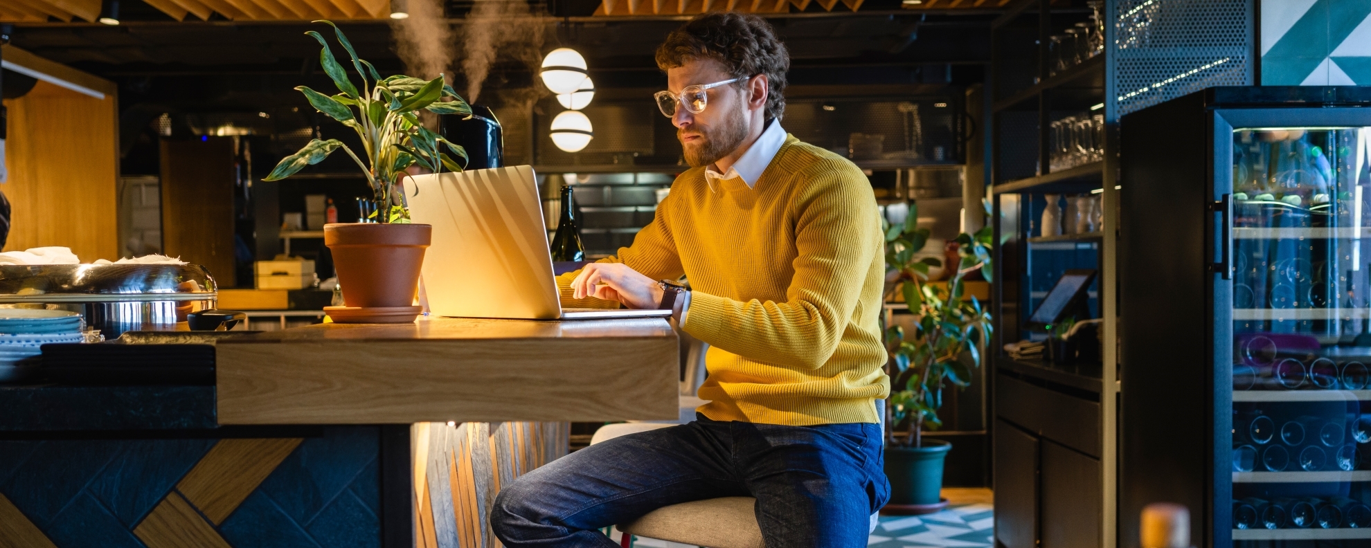 Business owner using laptop while sitting on seat at counter in cafe